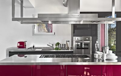 interior of a modern kitchen in the foreground the isalnd kitchen with gas hob and the extractor hood on the background the integrated oven and the sink cabinet