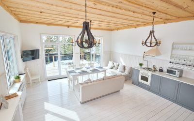 Wide angle of modern open living room interior overlooking floor to ceiling windows with white furniture and grey kitchen counters in minimalistic Scandinavian design by sunlight, copy space, nobody